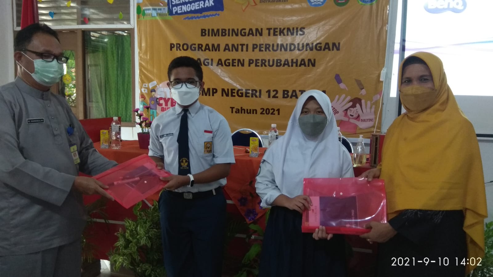 Pengawas Disdik Kota Batam, M. Nainggolan SPd dan Kepala Sekolah SMPN 12 Batam, Dra Nurmi, menyerahkan makalah kepada siswa yang ikut bimtek anti perundungan, Jumat (10/9)._IST