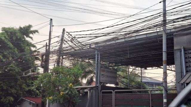 Kabel internet terpasang pada tiang listrik PLN di kawasan permukiman. Kabel internet terpasang pada tiang listrik PLN di kawasan permukiman.