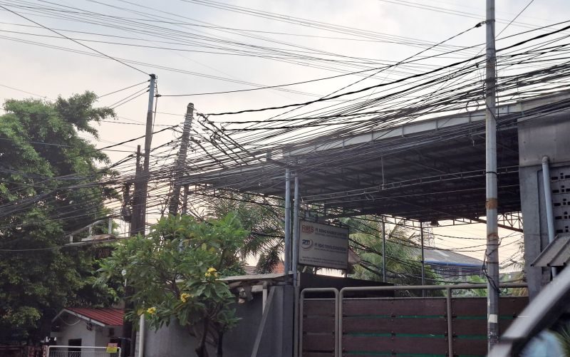 Kabel internet terpasang pada tiang listrik PLN di kawasan permukiman.
