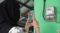Petugas PLN memeriksa kWh meter listrik di rumah pelanggan di Batam.