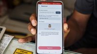 Petugas memindai wajah pelanggan saat registrasi kartu SIM berbasis biometrik di gerai operator seluler.