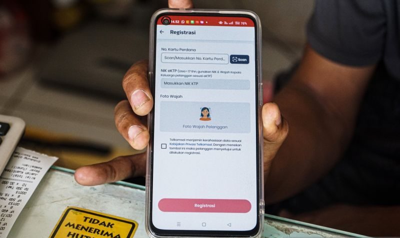 Petugas memindai wajah pelanggan saat registrasi kartu SIM berbasis biometrik di gerai operator seluler.