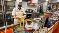 Teknisi PGN Gagas bersama staf Marugame Udon meninjau instalasi tabung silinder CNG berwarna kuning di area operasional restoran.