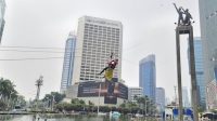 Enam aktivis Greenpeace Indonesia membentangkan spanduk tentang krisis iklim di Monumen Selamat Datang, Bundaran HI, Jakarta.