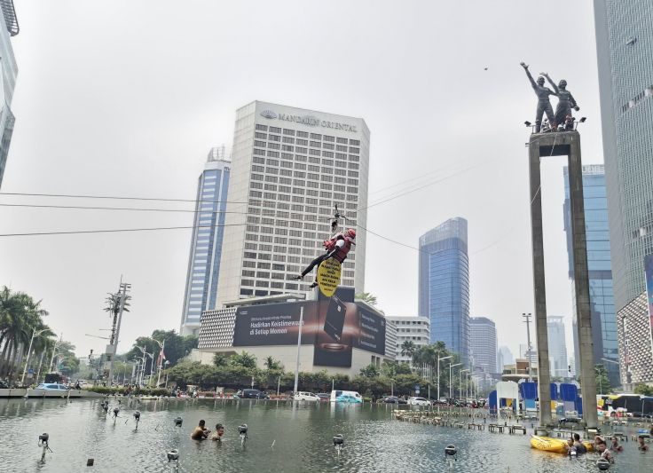 Enam aktivis Greenpeace Indonesia membentangkan spanduk tentang krisis iklim di Monumen Selamat Datang, Bundaran HI, Jakarta.